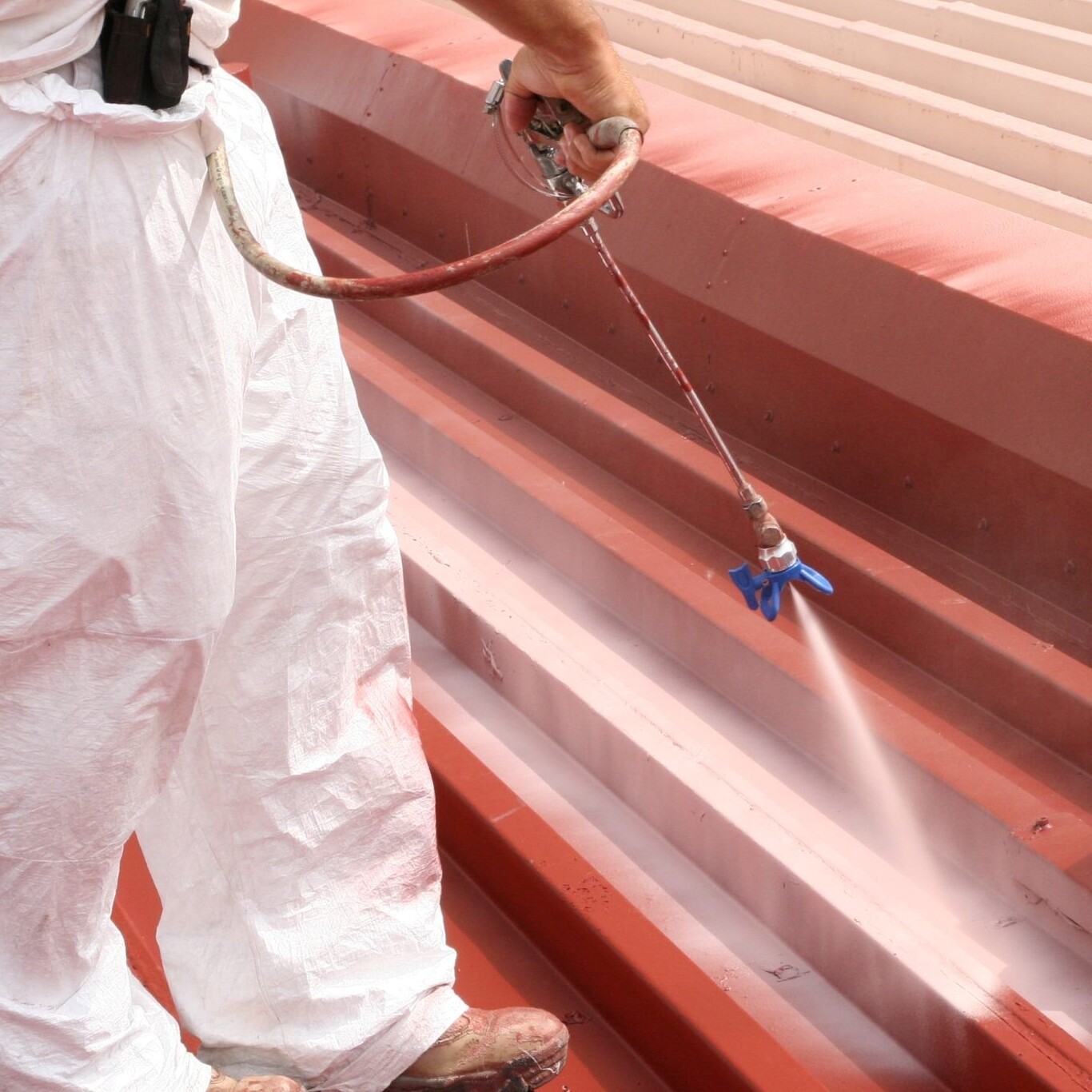 A Roofer Sprays a Roof Coating.