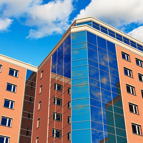 Modern glass reflective city business office buildings over blue sky with clouds